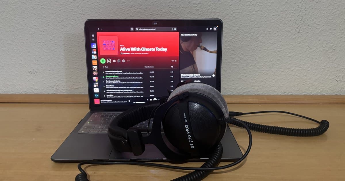 Portátil abierto con un álbum de Chris Potter en Spotify y unos auriculares Beyerdynamic DT 770 PRO apoyados sobre el teclado
